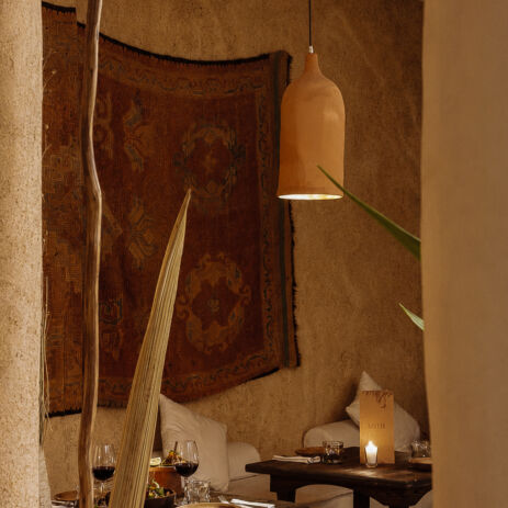 Salon d'AZULIK I INLA : tapisserie murale, lampe en terre cuite et tables dressées, Marrakech