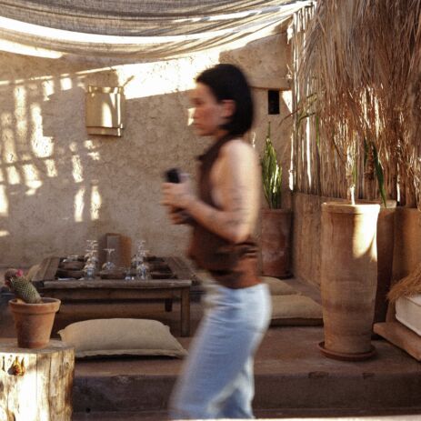 Patio d'AZULIK I INLA : porte en bois, palmes séchées et banquettes au cœur de la médina de Marrakech